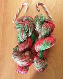 hand-dyed-skein-of-wool-in-red-and-green-with-candy-canes-above-it.