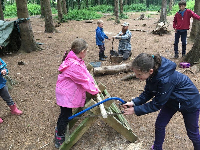 Children sawing wood at Forest School Holiday Club