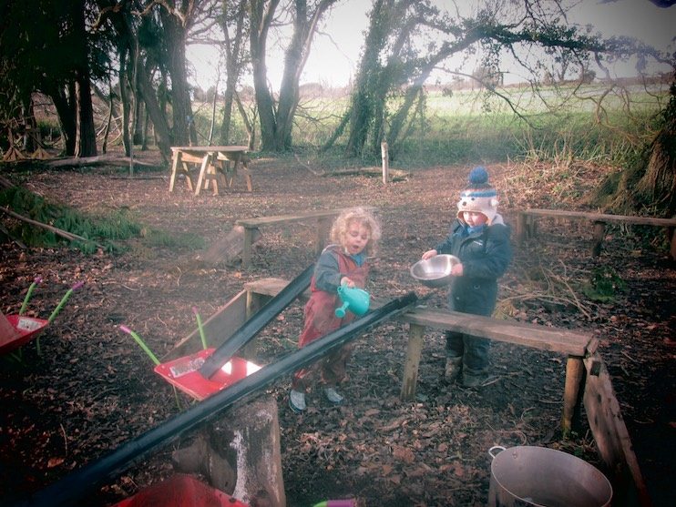 Children playing with water tunnels at forest school