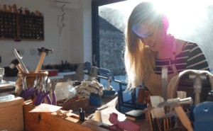 women-working-with-jewellery-in-workshop-with-sun-shining-in-behind-her.