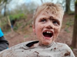 blond-haired-boy-covered-in-mud-pulling-funny-face.